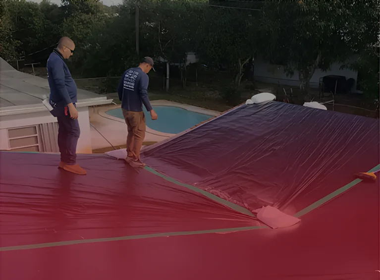 Two workers tarping a storm-damaged residential roof